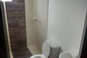 a white bathroom with a toilet and a shower at Apartamento Amoblado 3 hab 2 baños con excelente vista montañas cafeteras acogedor ambiente familiar, piscinas niños adultos, parqueadero, BBQ y ascensor con muy buena iluminación natural in Hojas Anchas