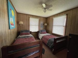 two beds in a room with wooden walls and windows at SOUTHERN STAR cottage in Hatteras