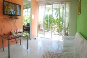 a living room with a tv on a wall and a table at Casa de Verano Condominio Mediterráneo en Carmen de Apicalá in Carmen de Apicalá