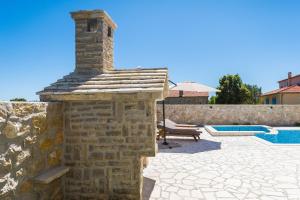 uma parede de pedra com uma lareira de tijolos ao lado de uma piscina em Villa St Vid 2 em Privlaka