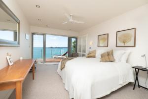 a bedroom with a bed and a desk and a large window at Heaven NZ Luxury Accommodation in Russell +51 photos
