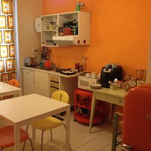 una cucina con pareti arancioni, armadi bianchi e tavoli di Casa Olivia a Firenze