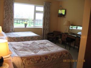 a hotel room with two beds and a desk and a window at Birchwood B&B in Kells