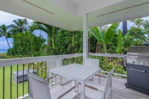 una mesa blanca y sillas en un porche con parrilla en Hanalei Beachfront Cottage home, en Hanalei
