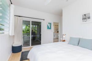 a white bedroom with a bed and a window at Hanalei Beachfront Cottage home in Hanalei