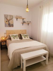 Dormitorio blanco con cama y mesa en ALMERIA SOL Y SUR APARTMENTO - Netflix y Parking GRATUITO en Almería