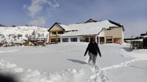 a person walking in the snow in front of a house at Hotel La Faustina-Caviahue in Caviahue +57 photos