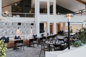a restaurant with tables and chairs in a building at Rydges Formosa Auckland Golf Resort in Auckland
