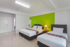 two beds in a room with a green wall at CW Mansion Phuket in Phuket Town