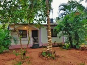 a house with a palm tree in front of it at Coco inn Goa in Candolim