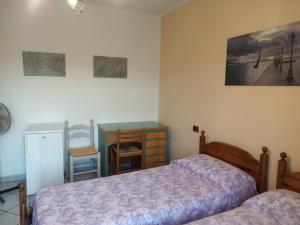 a bedroom with two beds and a table and a desk at Bed & breakfast Mezzaluna in Feletto