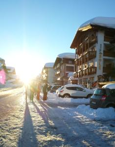 een groep mensen die door een met sneeuw bedekte straat lopen bij Hotel Sole in Passo del Tonale