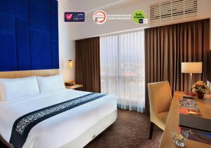 um quarto de hotel com uma cama grande e uma secretária em Swiss-Belinn Malang em Malang