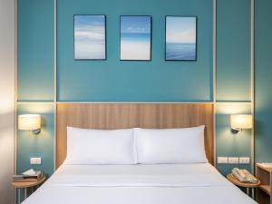 a bed in a hotel room with three pictures on the wall at Hotel Ibis Samui Bophut in Bophut