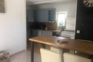 a kitchen with a wooden table and white chairs at Maison au pied des dunes, 200m de la plage in Montmartin-sur-Mer