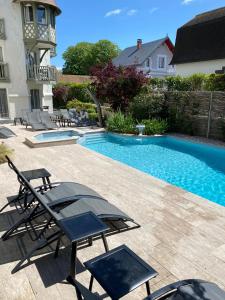 a swimming pool with chairs next to a house at Villa Augeval Hôtel de charme & Spa in Deauville