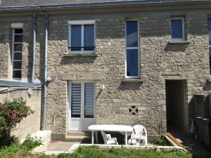 een stenen huis met een tafel en stoelen ervoor bij gîte iaorana - maison en centre ville in Valognes