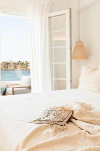 a white bed with a book and flowers on it at Apartamento Las Golondrinas Arenal - Adults Only in Arenal d'en Castell