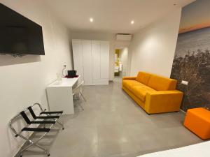 a living room with a yellow couch and a tv at Torre del mare Rooms in Bergeggi