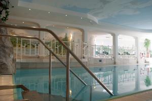 a swimming pool with a staircase leading to a large indoor pool at Sporthotel Xander in Leutasch