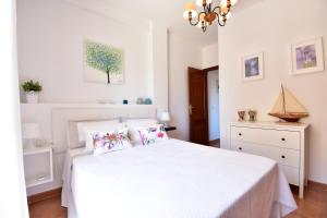 ein weißes Schlafzimmer mit einem weißen Bett und einem Kronleuchter in der Unterkunft Disfrute de las playas y el golf en nuestro adosado en Islantilla - Costa de la Luz in Lepe + 32 Fotos