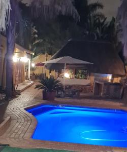 a blue swimming pool in a yard at night at 3 Brothers B&B in Edenvale