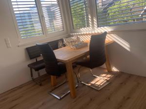 uma mesa de madeira e cadeiras num quarto com duas janelas em Ferienwohnung Beate Hassler em Berg im Drautal
