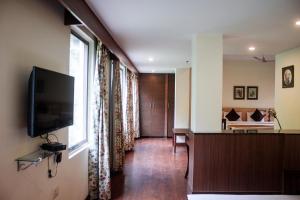 a living room with a television and a bedroom at Savoy Greens Jabli in Kasauli
