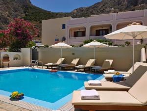 a pool at a hotel with chairs and umbrellas at Studios Marios in Kamari