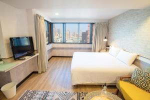 a hotel room with a bed and a tv at New Generation of Boutique Business Hotel in Kaohsiung