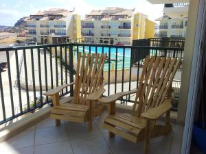 - deux chaises en bois sur un balcon avec vue sur la piscine dans l'établissement Vista Oceano - Boa Vista Island, à Sal Rei