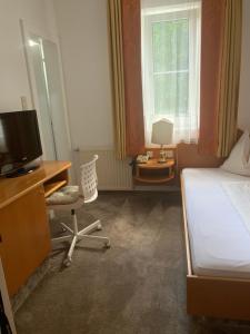 Schlafzimmer mit einem Bett und einem Schreibtisch mit einem TV in der Unterkunft Villa Christina in Pörtschach am Wörthersee