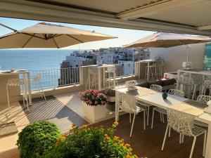 un balcón con mesas, sombrillas y el océano en Malù Bed&Breakfast, en Polignano a Mare