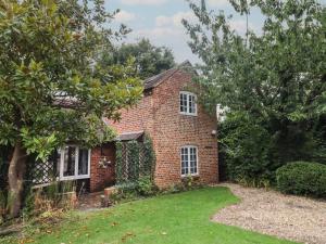 an old brick house with a grass yard at The Coach House Apartment in Tewkesbury