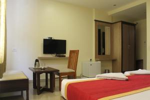 een hotelkamer met een bed, een bureau en een tv bij HOTEL GREEN TREES in Bangalore +26 foto's