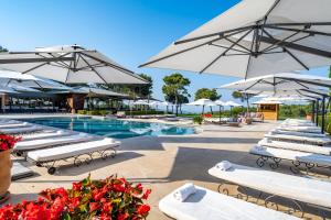 - une piscine avec des chaises longues blanches et des parasols dans l'établissement L'Hôtel & Spa du Castellet, au Castellet