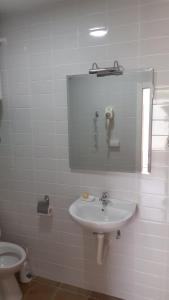a white bathroom with a sink and a toilet at Apartman PETI PUK in Valjevo