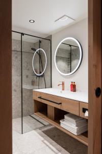 ein Bad mit einem Waschbecken und einem Spiegel in der Unterkunft Hotel Salzburg in Saalbach-Hinterglemm