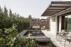 un patio trasero con piscina, mesa y sillas en The Olivar Suites en Mesongi