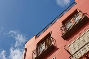 Puerto的住宿－Maisonette Tazacorte，粉红色的建筑,设有两个阳台,享有蓝色的天空