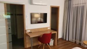 Zimmer mit einem Schreibtisch, einem TV und einem roten Stuhl. in der Unterkunft Der Adler in Lauchringen