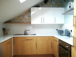 eine Küche mit Holzschränken und einem Waschbecken in der Unterkunft Harrogate Toffee Loft in Harrogate