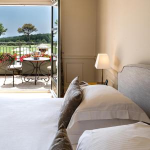a bedroom with a bed and a patio with a table at L'Hôtel & Spa du Castellet in Le Castellet