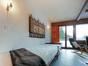 1 dormitorio con 2 camas, silla y ventana en Apartment Pigne 1 by Interhome, en Verbier