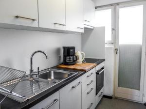 una cocina con armarios blancos y fregadero en Apartment Chesa Ova Cotschna 304 by Interhome, en St. Moritz