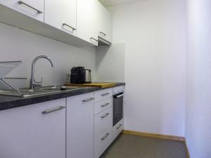 a kitchen with white cabinets and a sink at Apartment Chesa Ova Cotschna 305 by Interhome in St. Moritz