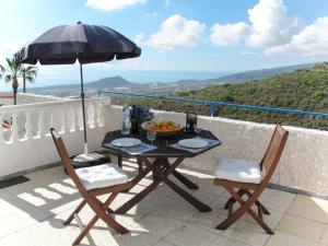 a table and chairs with an umbrella on a balcony at Apartment Las Cuevecitas - CND110 by Interhome in Icoro