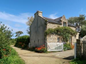 een oud stenen huis met een wit hek bij Holiday Home Keranna - LPM102 by Interhome in Lampaul-Ploudalmézeau