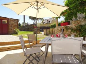 stół i krzesła z parasolem na patio w obiekcie Holiday Home La Pailloussette - A w mieście Cancale