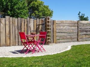 deux chaises rouges assises à côté d'une clôture en bois dans l'établissement Holiday Home La Pailloussette - A, à Cancale